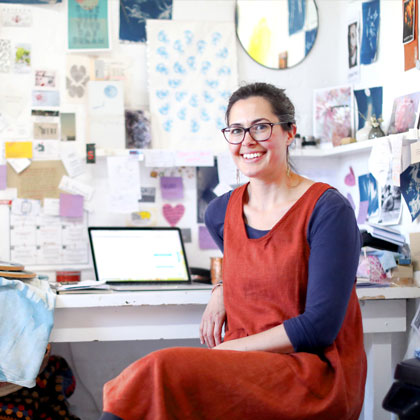 Woman wearing glasses smiling in her craft workshop